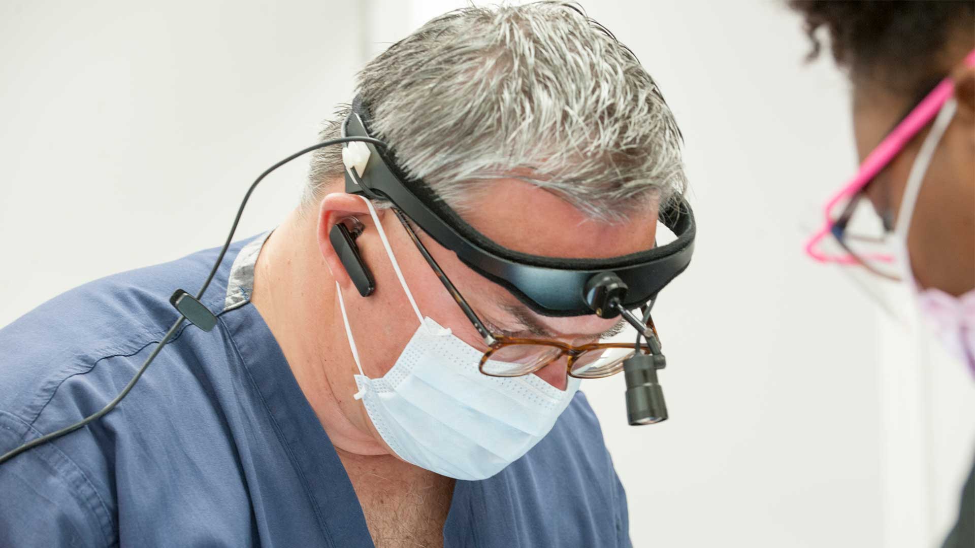 oral surgeon in surgery wearing headlamp and face mask